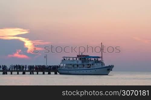 Timelapse of touristic ship sailing to pier, unboarding and boarding passengers and pushing off. Sea travel at sunset