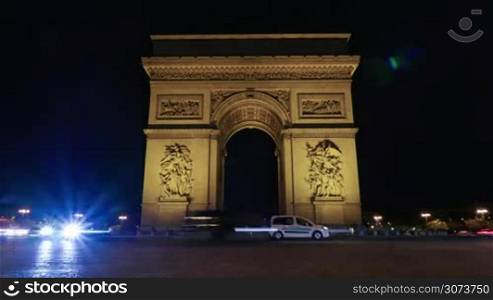 Timelapse shot of car traffic by the Triumphal Arch of the Star illuminated at night. One of the most famous monuments in Paris, France