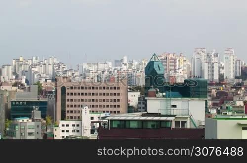 Timelapse shot of cityscape of Seoul in Republic of Korea. Highrise buildings and working construction cranes. Sun shining over the city and clouds sailing