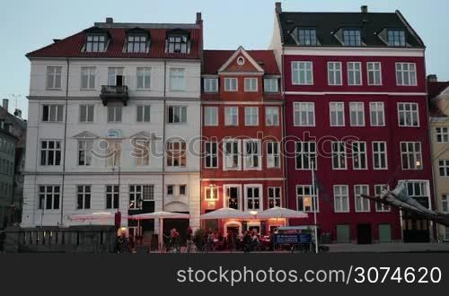 Timelapse shot of of evening coming to the city. View to the classic style building facades in white and red colors with outdoor cafe and parked bikes nearby, people passing by