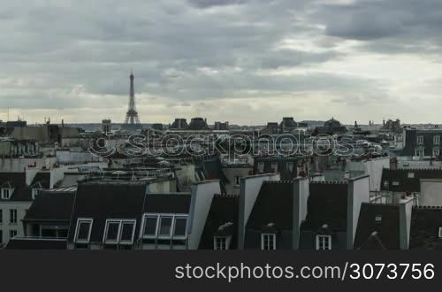 Timelapse shot of Paris panorama with typical houses in foreground, Eiffel Tower in the distance. Dark clouds sailing over the city