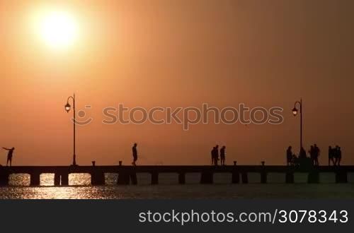 Timelapse shot of people walking on the pier at sunset and in the dusk