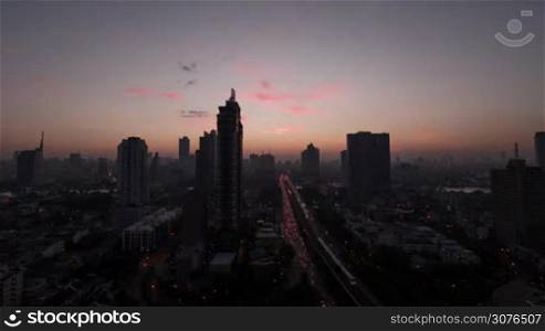 Timelapse shot of sun rising over Bangkok, Thailand. Dawn in the capital city with intense traffic and high-rise architecture