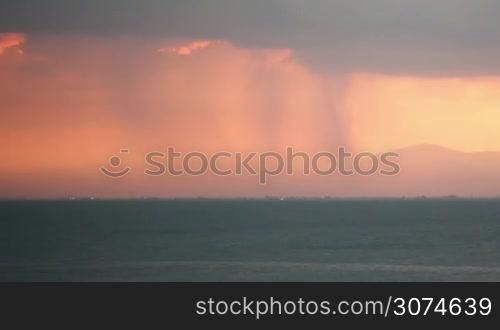 Timelapse shot of thunderstorm. Rain pouring from heavy clouds and lightnings striking over the coastal city and sea