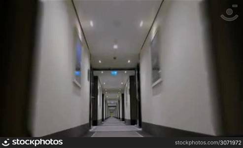 Timelapse steadicam and low angle shot of moving through the modern and light hotel corridor to the doorway
