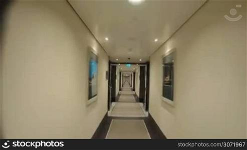 Timelapse steadicam and wide angle shot of moving along the empty light hotel corridor with pictures hanging on the walls