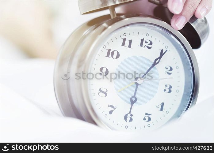 Times concept, closeup of alarm clock on bed. Wakeup, deadline, good morning concept.