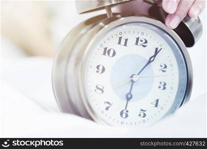 Times concept, closeup of alarm clock on bed. Wakeup, deadline, good morning concept.