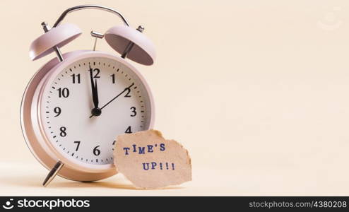 times up text torn paper near alarm clock against beige background