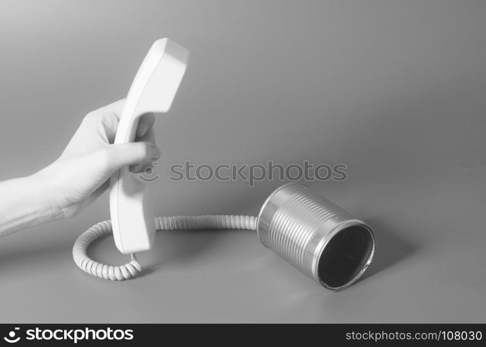 Tin can phone handset holding hand on gray