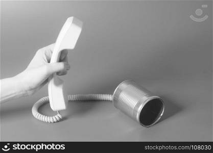 Tin can phone handset holding hand on gray
