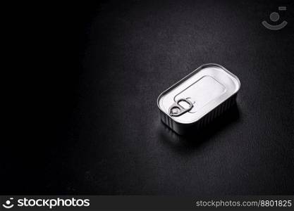 Tin or aluminum rectangular can of canned food with a key on a dark concrete background