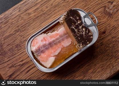 Tin or aluminum rectangular can of canned salmon with a key on a dark concrete background