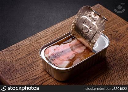 Tin or aluminum rectangular can of canned salmon with a key on a dark concrete background
