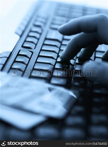 Tinted blue photo with computer keyboard, credit cards and hands