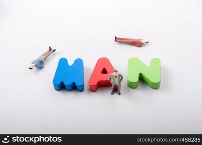 Tiny figurine of men beside colorful wooden letters say MAN