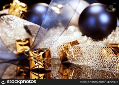 tiny golden christmas present in front of christmas decoration. tiny shiny golden christmas present in front of christmas decoration with christmas balls and ribbons