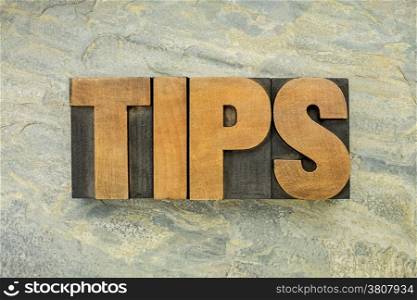 tips - a word in vintage letterpress wood type on a green slate rock background