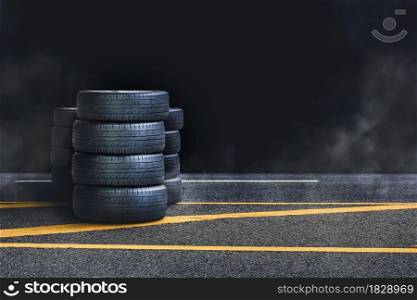 Tire pile on the asphalt road with smoke at night and black background,copy space
