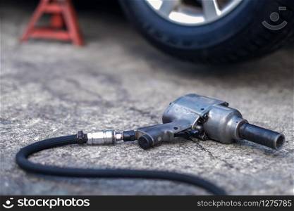 Tire Replacement concept. Electric Screwdriver Wrench for Wheel Nuts lay on the Floor in Garage. Car Maintenance and services