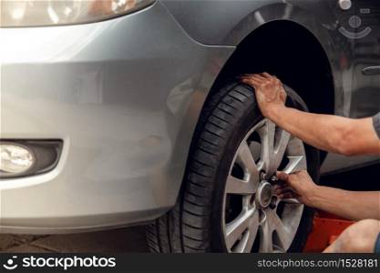 Tire Replacement concept. Mechanic Working his Job with Wheel in Garage. Car Maintenance and services