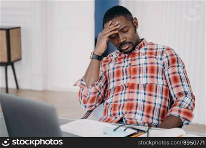 Tired african american businessman suffer from headache at workplace at laptop. Frustrated overworked black male guy touching head thinking about business problem, closed eyes. Stress at work concept. Tired african american man suffer headache at laptop thinking about business problem. Stress at work