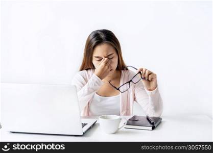 Tired and stressed young asian woman feel pain eyestrain and rubbing her eyes and take off her glasses while sitting at her working place