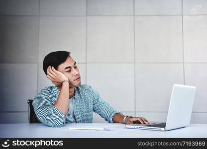 Tired and Stressed Young Businessman Sitting on Desk in Office with Computer Laptop. Exhausted Man Boring a Hard Work