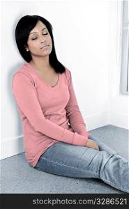Tired black woman sitting against wall with eyes closed
