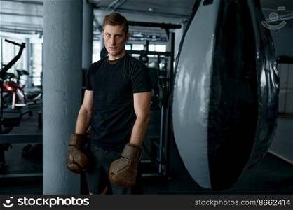 Tired boxer with masculine body posing in boxing gloves demonstrating strength and power. Tired boxer with masculine body in boxing gloves