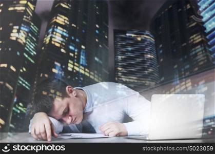 Tired business man is sleeping at his table with laptop. Exhausted businessman sleeps
