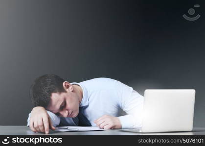 Tired business man is sleeping at his table with laptop. Exhausted businessman sleeps