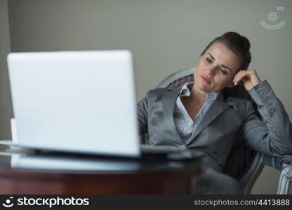 Tired business woman sitting in hotel room and looking on laptop