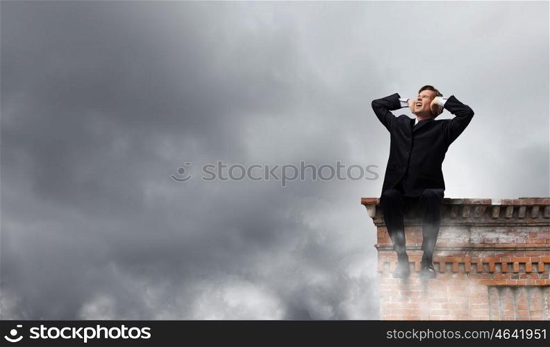 Tired businessman. Frustrated businessman on building top closing ears with hands