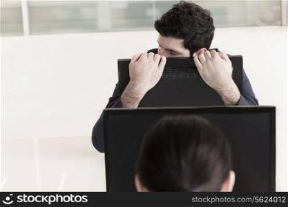 Tired businessman holding his computer monitor and resting