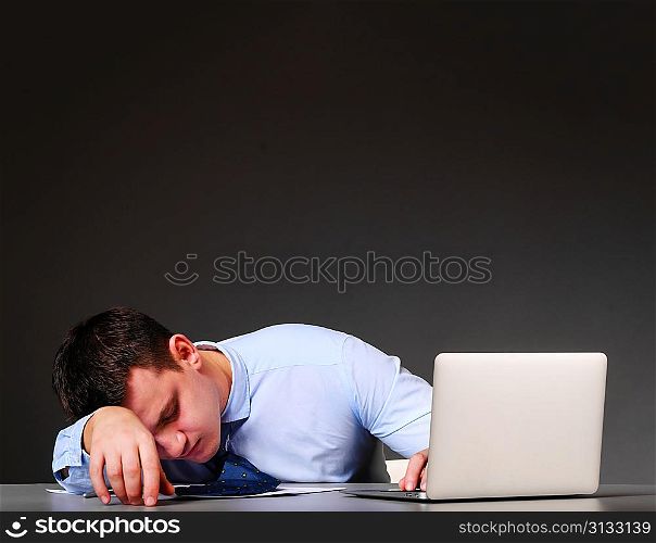tired businessman is sleeping at his table with laptop