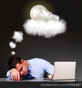 tired businessman is sleeping at his table with laptop and a bulb above his head