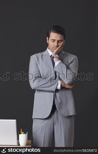 Tired businessman sleeping while standing by office desk