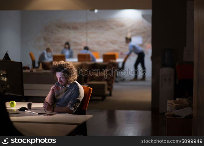 Tired businessman working late doing overtime in office at night drinking coffee to go on.