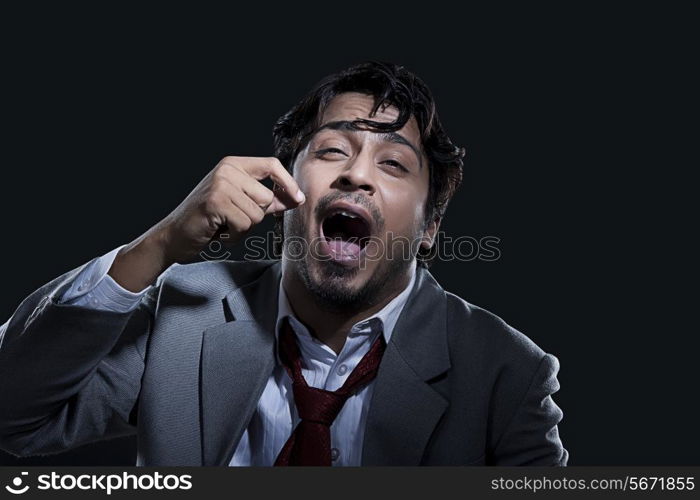 Tired businessman yawning over black background