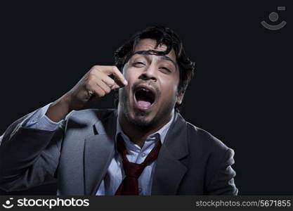 Tired businessman yawning over black background