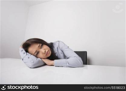 Tired businesswoman leaning at office desk