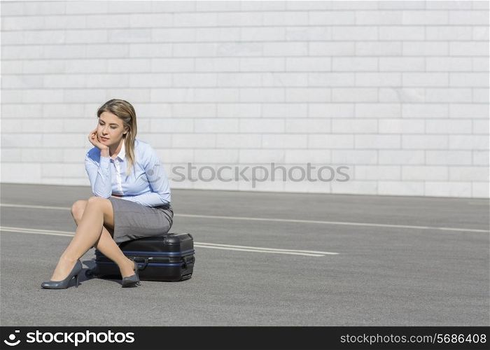 Tired businesswoman sitting on luggage