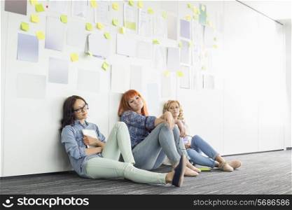 Tired businesswomen sitting on floor in creative office