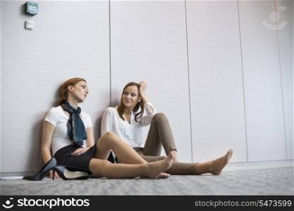 Tired businesswomen sitting on floor in office
