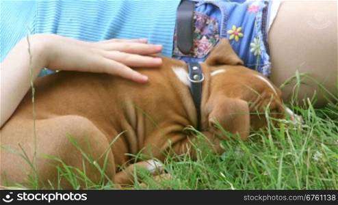 Tired child with puppy relaxing on the grass in summer garden