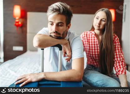 Tired couple sits on bed with suitcase prepared for vacation. Fees on journey concept. Luggage preparation. Travelling or tourism. Tired couple sits on bed with suitcase