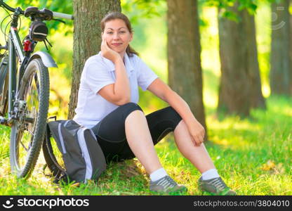 tired cyclist resting in a park near a tree
