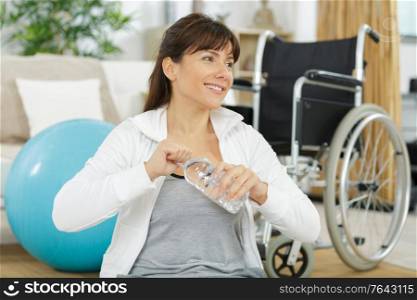 tired disabled woman drinking water after sport