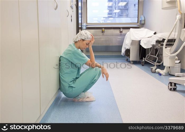Tired doctor sitting alone in hallway